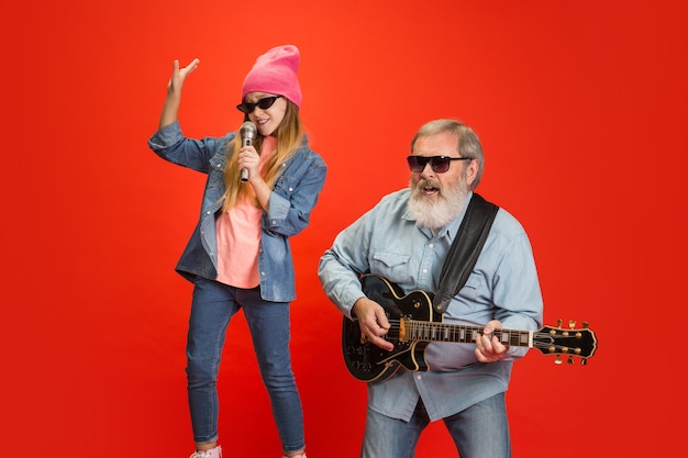 Playful, stylish. Senior man spending happy time with granddaughter in neon.