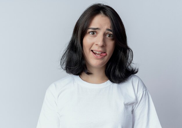 playful young pretty caucasian woman showing tongue looking at camera isolated on white