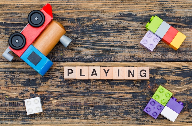 Playing toys concept with wooden cubes, kid toys on wooden background flat lay.