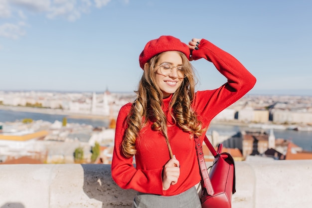 Free photo pleased caucasian girl plays with brown hair in sunny day in european capital