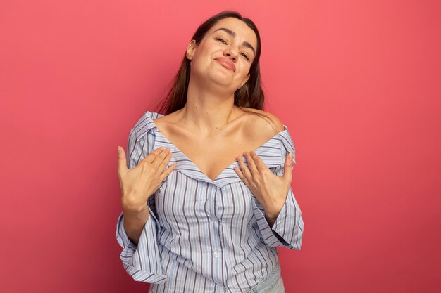 Pleased pretty caucasian woman  hands on chest on pink