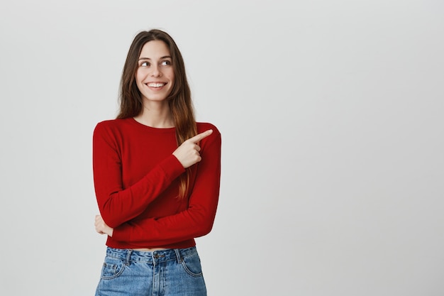 Pleased smiling, attractive woman pointing and looking upper right corner