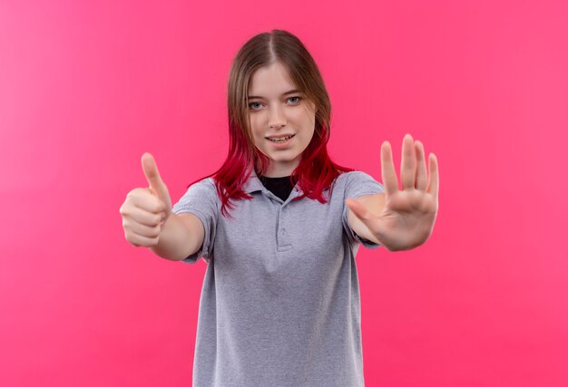 Pleased young beautiful girl wearing gray t-shirt showing different gestures on isolated pink background