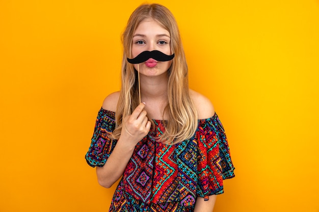 Pleased young blonde slavic girl holding fake mustache on stick 