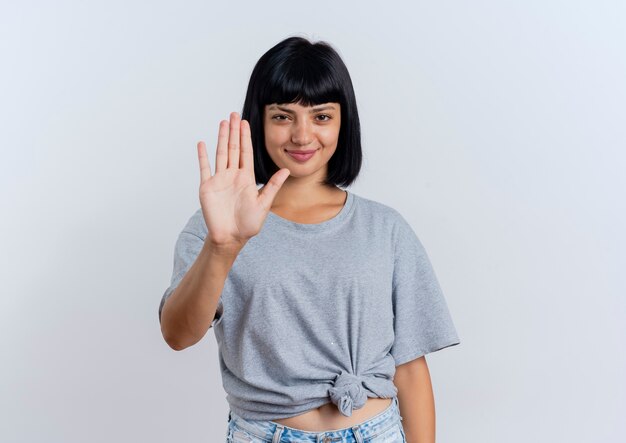 Pleased young brunette caucasian woman gestures stop hand sign