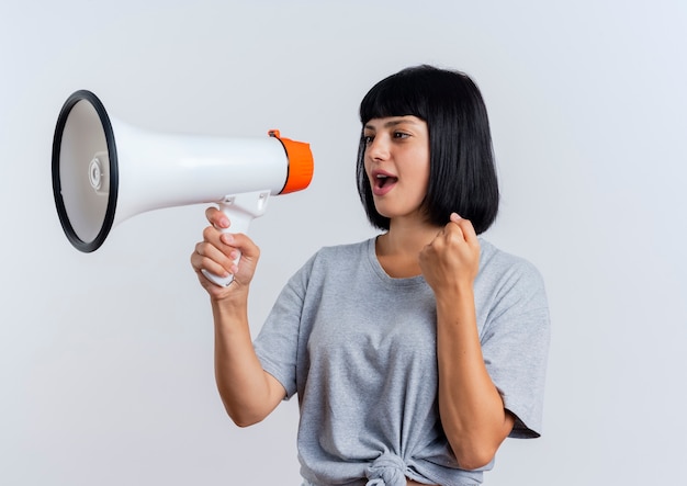 Pleased young brunette caucasian woman keeps fist holding and looking at loud speaker