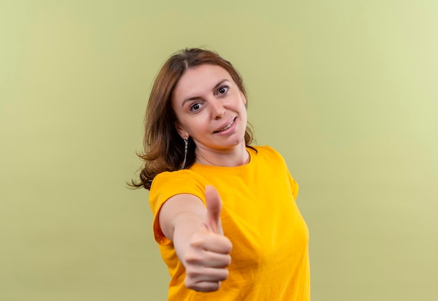 Pleased young casual woman showing thumb up on isolated green space with copy space