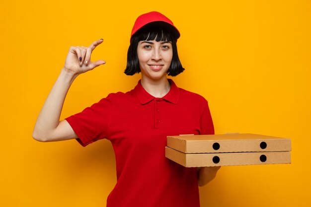 Pleased young caucasian delivery girl holding pizza boxes and pretending to keep something 