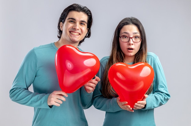 Pleased young couple on valentines day holding heart balloons isolated on white background