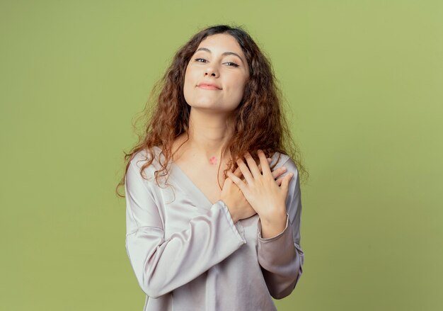 Pleased young pretty female office worker putting hands on shoulder isolated on olive green