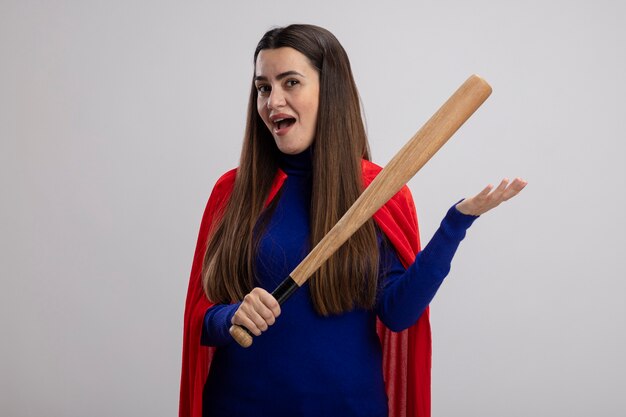 Pleased young superhero girl holding baseball bat isolated on white background