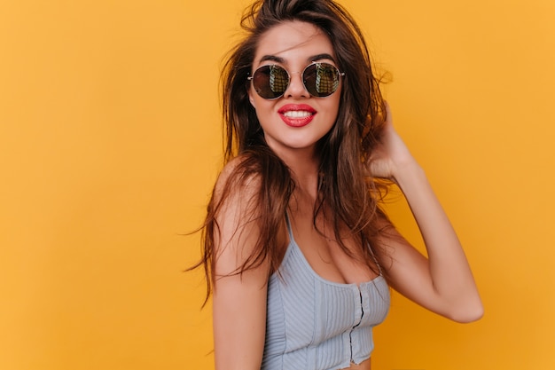 Pleased young woman with inspired smile playing with dark hair