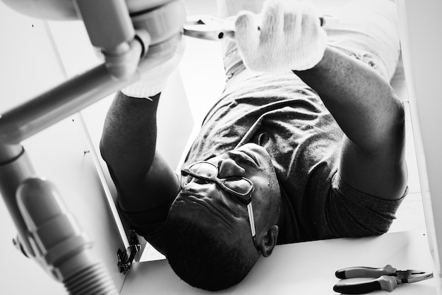 Free photo plumber man fixing kitchen sink