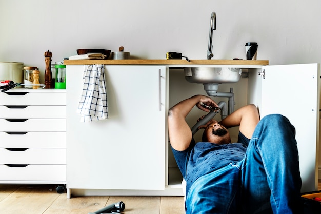 Free photo plumber man fixing kitchen sink