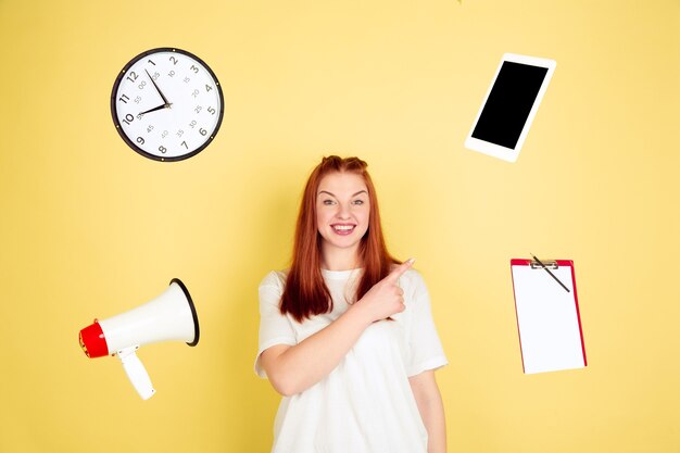 Pointing, choosing. Caucasian young woman's portrait on yellow studio