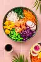 Free photo pokea bowl with fresh salmon rice chuka salad edamame beans carrots and red cabbage healthy food bowl on pink background vertical