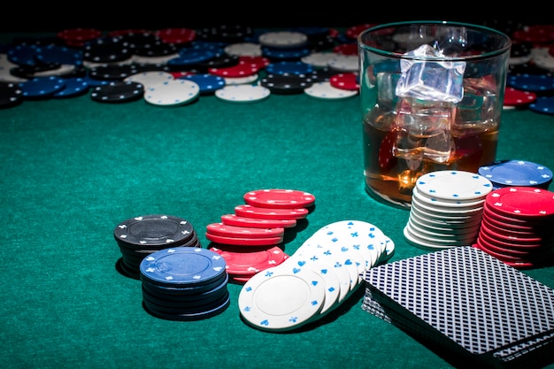 Poker chips and glass of whiskey on green poker table