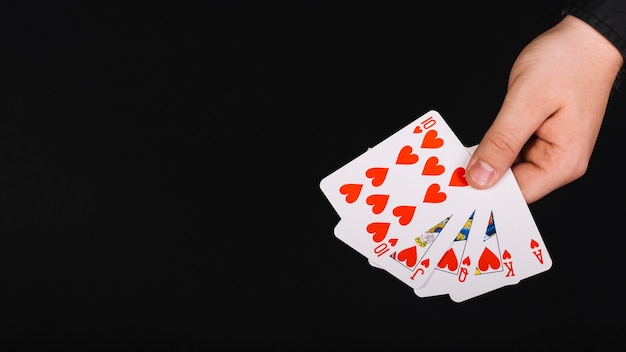 Free photo poker player's hand with royal flush heart on black background