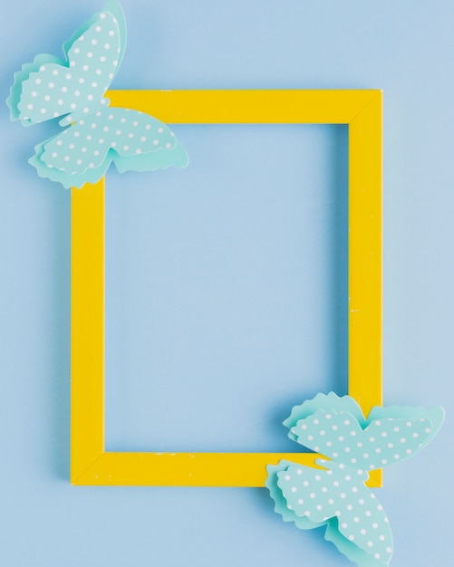 Free Photo polka dotted butterfly on yellow border frame over blue background