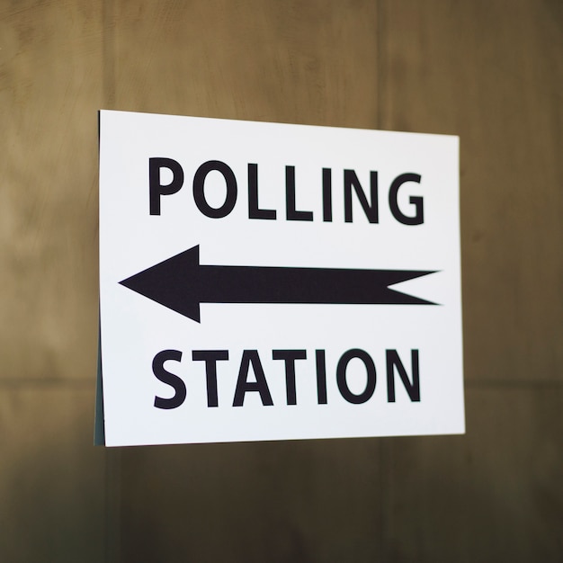 Free photo polling station sign with direction on wooden wall close-up