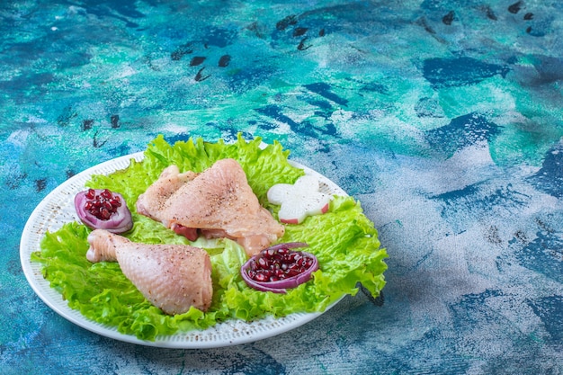 Pomegranate arils, lettuce leaves with onion ring next to chicken meat on a plate