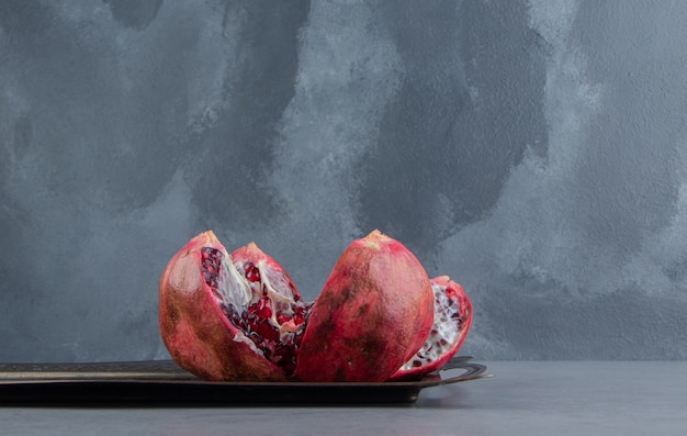 Free photo pomegranate broken open on an ornate tray on marble