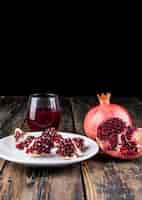 Free photo pomegranate juice and pomegranate on wooden table