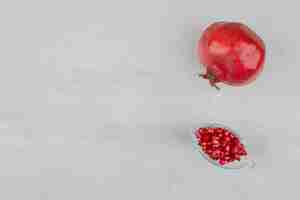 Free photo pomegranate seeds in glass and pomegranate on white.