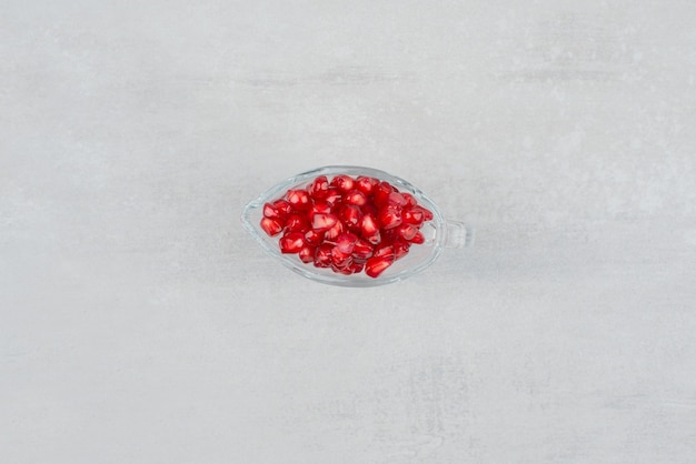 Pomegranate seeds in glass on white surface