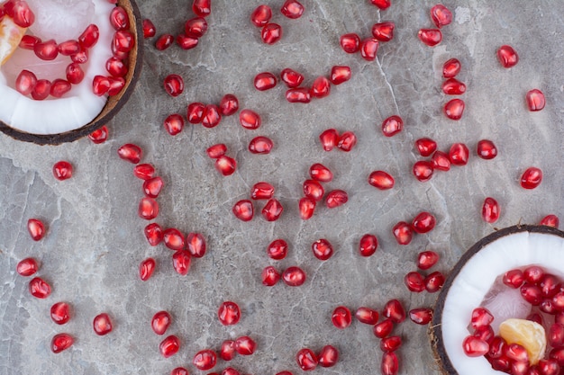 Pomegranate seeds inside coconuts and on surface. 