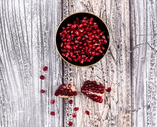 pomegranate seeds in plate top view on wooden table