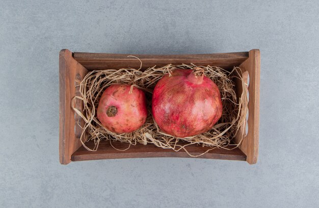 Pomegranates in a wooden basket on marble 