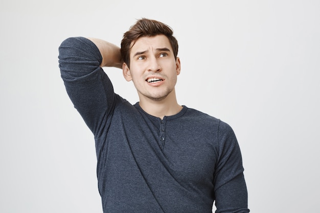 Free photo pondering concerned man thinking, scratch back of head indecisive