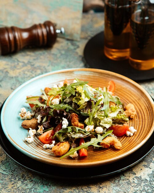 pop corn salad with fried shrimp arugula tomatoes and pop corn on plate