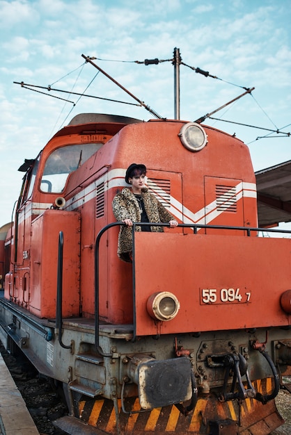 Free photo pop punk aesthetic portrait of woman posing by locomotive