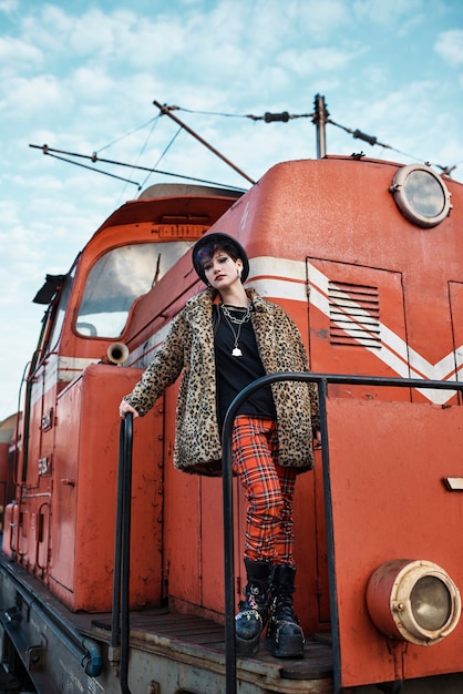 Pop punk aesthetic portrait of woman posing by locomotive