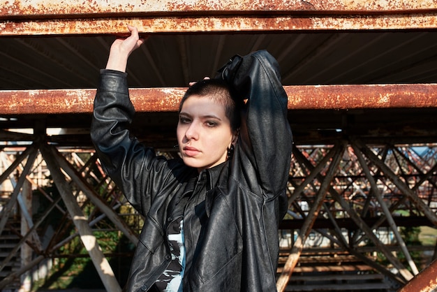 Free photo pop punk aesthetic portrait of woman posing on metal structure