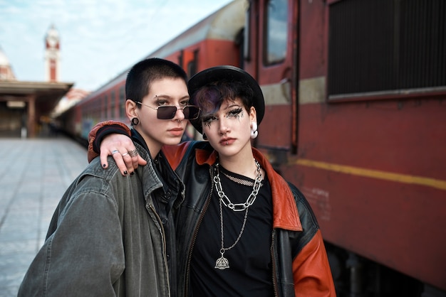 Free Photo pop punk aesthetic portrait of women posing by a locomotive