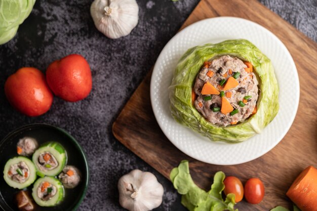 Pork cabbage soup with carrots, chopped green onions, cucumber in a wooden plate on a wooden plate