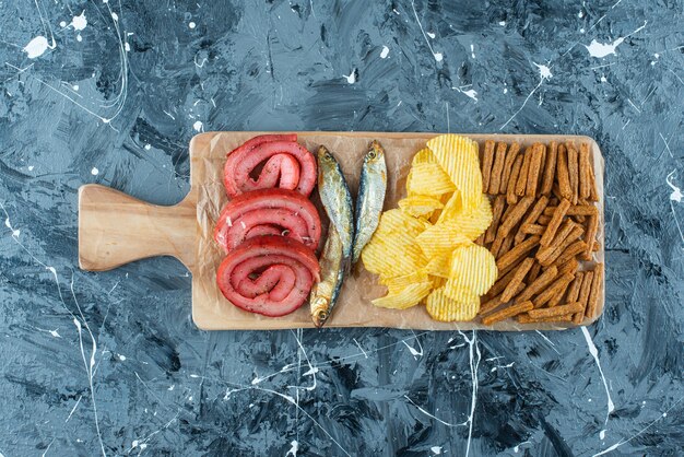 Pork lard, fish, chips and breadcrumbs on cutting board on blue.