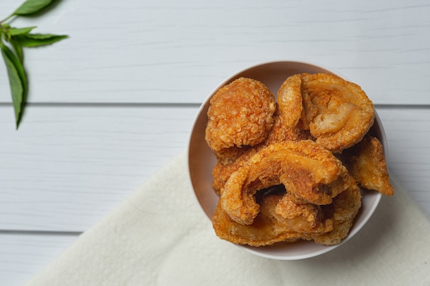 Pork rind in white bowl on white wooden floor