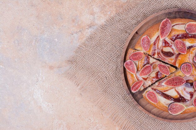 A portion of pie with purple figs in a wooden platter