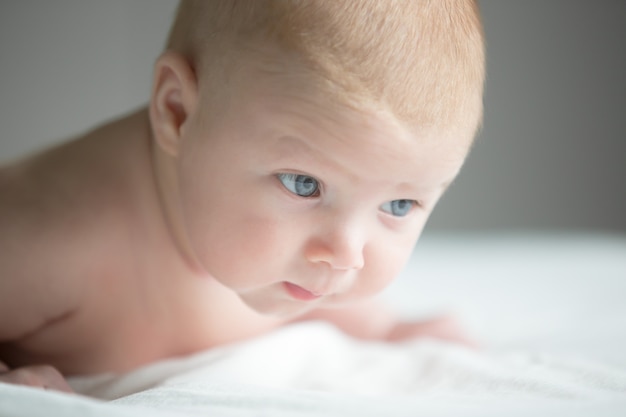 Portrait of 3 month newborn trying to crawl, hold head up