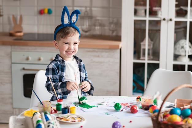 Portrait of adorable little boy painting eggs for easter