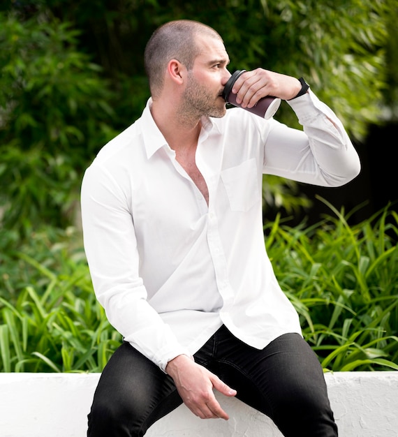 Free Photo portrait of adult male drinking coffee outdoors