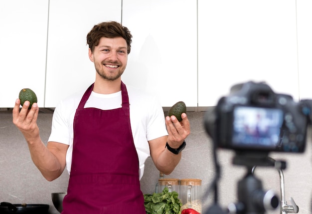 Portrait of adult male holding avocados on camera