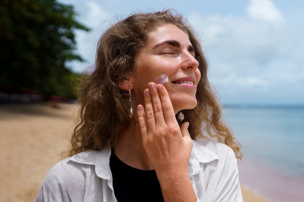 Free Photo portrait of adult woman applying lotion on sunburn skin