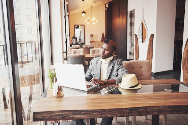 Portrait of african american man sitting at a cafe and working on a laptop