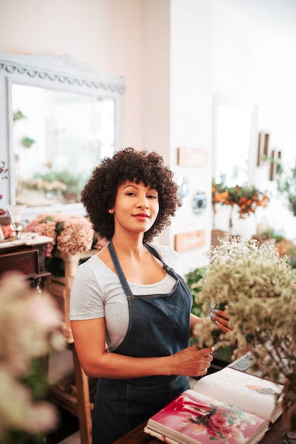 Free photo portrait of an african woman with bunch of flowers looking at camera