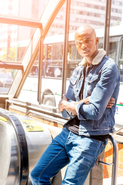 Free photo portrait of a african young man standing at the entrance of subway looking away